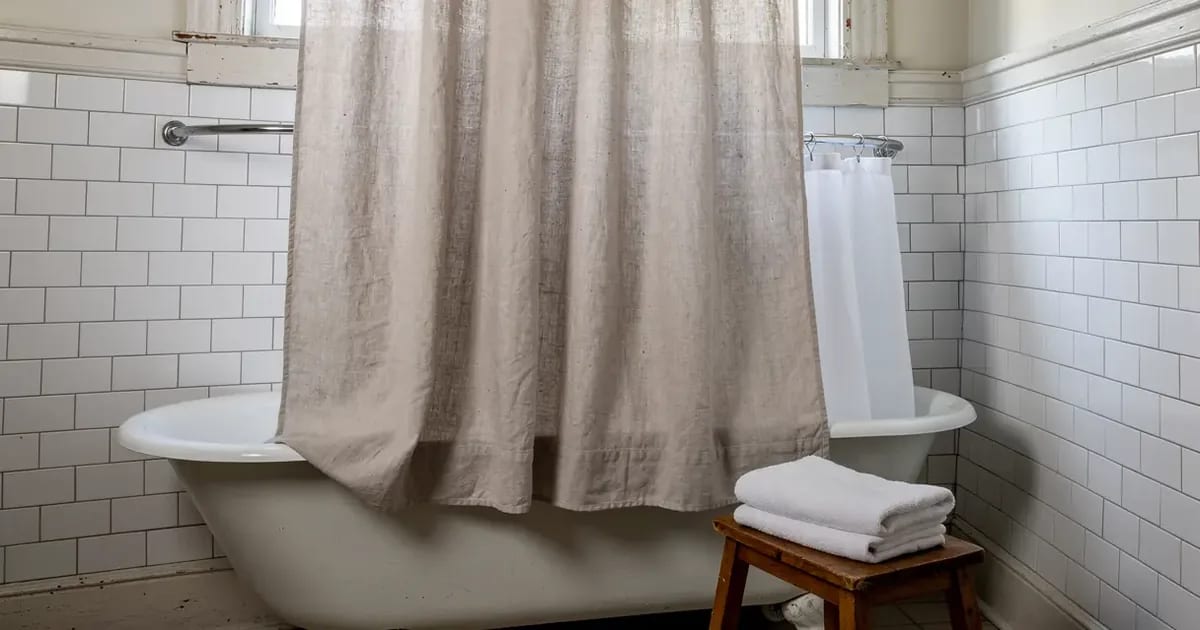Rideau de douche en lin naturel devant une baignoire sur pattes, avec une doublure blanche en tissu à l'intérieur