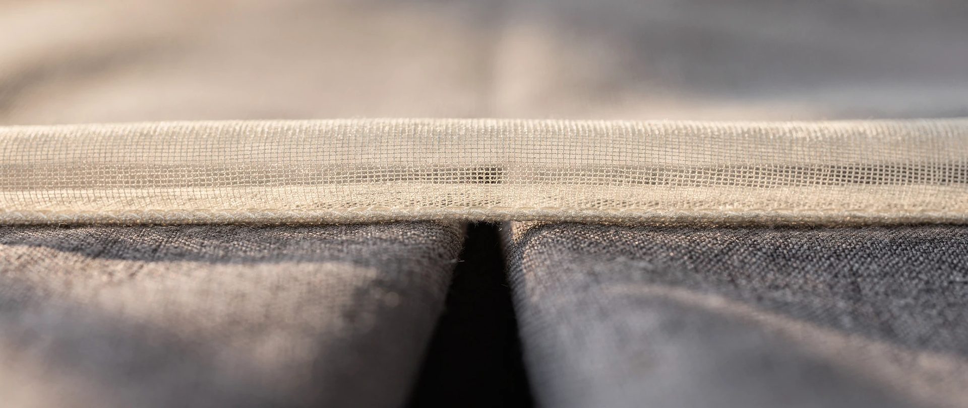Sheer ivory voile layered over a heavy dove-grey lined curtain in close-up.
