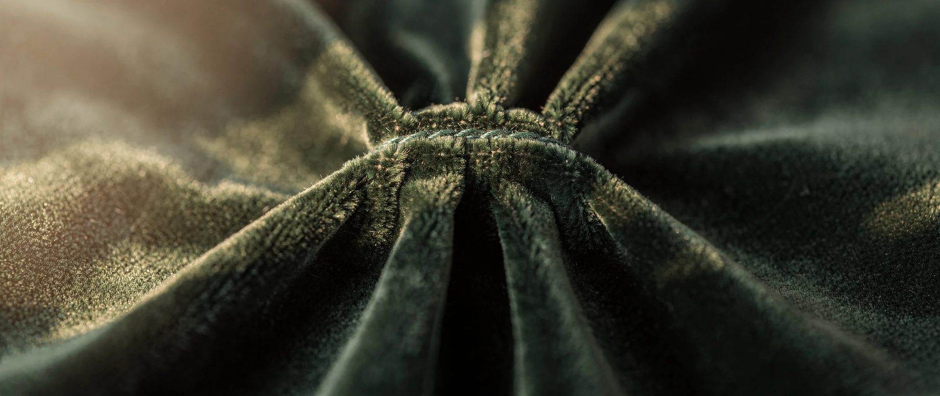 Hand-sewn pinch pleat in bottle-green cotton velvet, with folds fanning out from the stitched base.