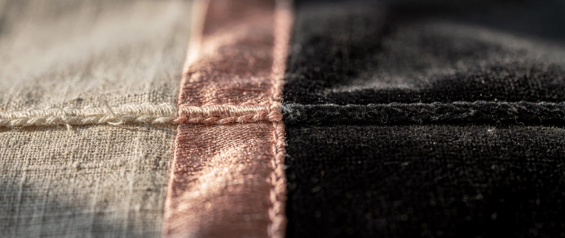 Three fabrics meeting at a seam: raw linen, blush silk and charcoal velvet.