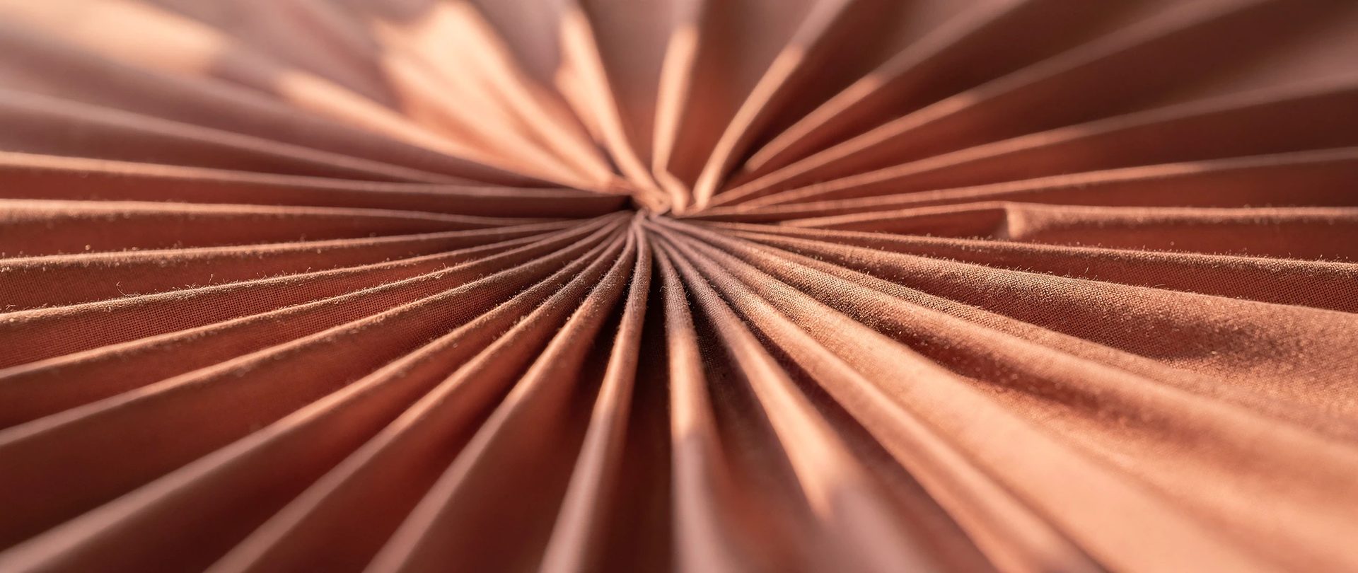 Copper-toned cotton pleats radiating in a fan from a single gathered point.