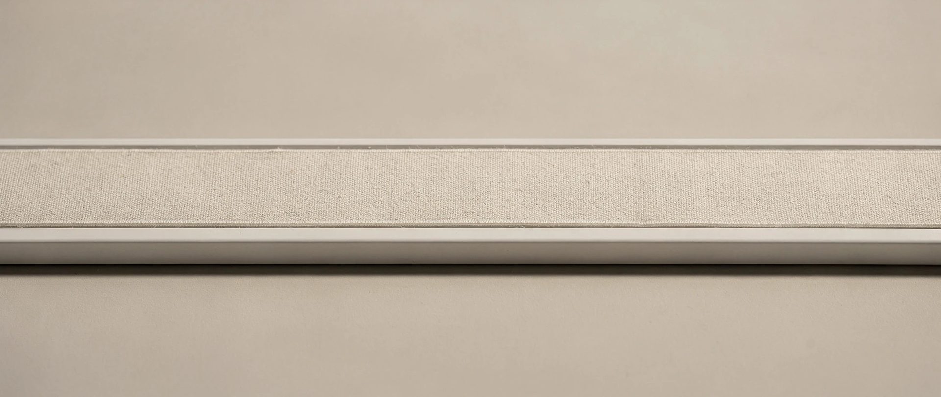 Matte-white aluminium curtain track with a flat greige linen heading, clean and minimal.