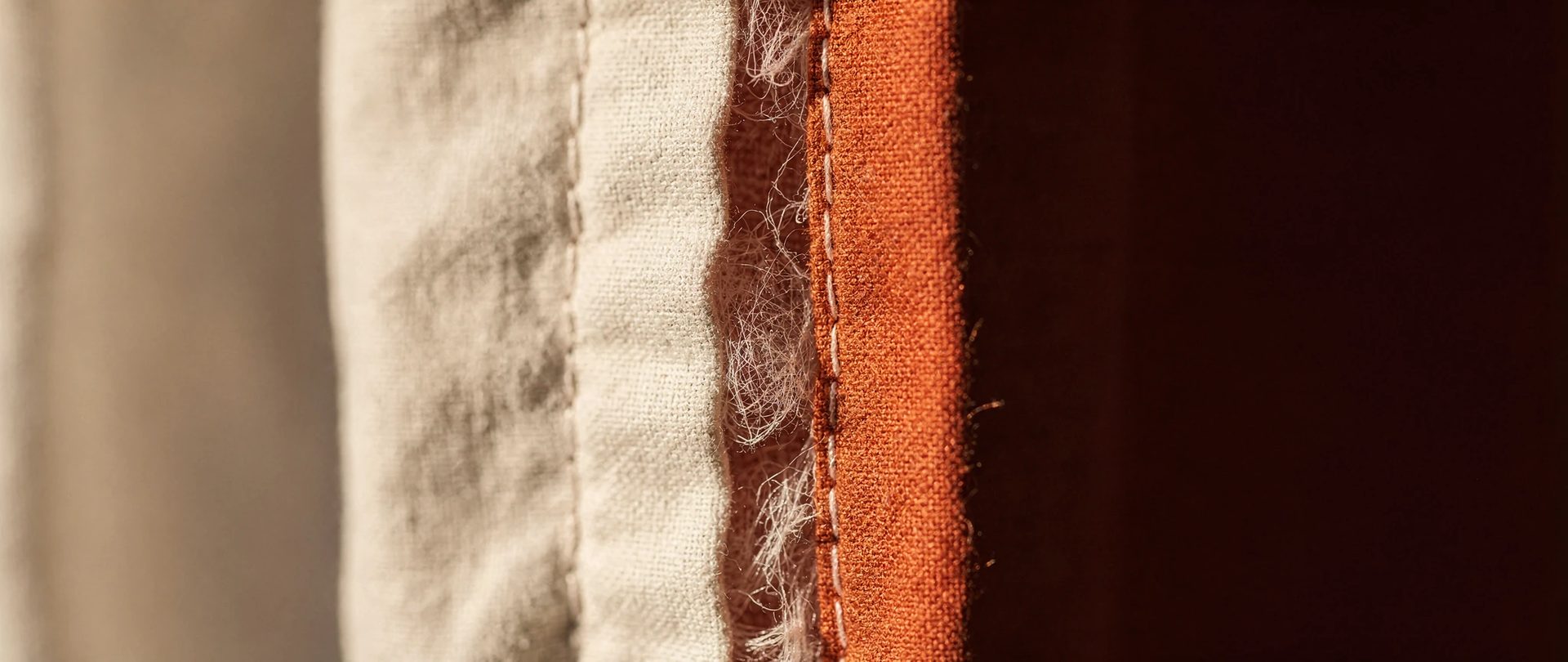 Doublure crème piquée à un tissu orange rouille, avec le molleton qui dépasse entre les couches.
