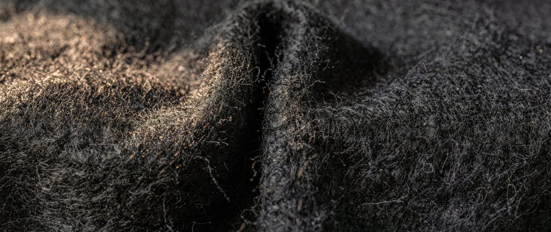 Dense, fuzzy charcoal felted wool with a single soft fold.