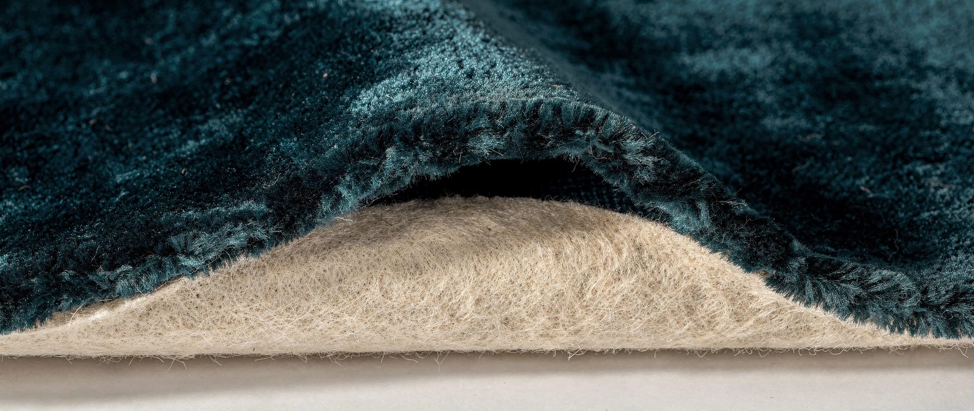 Heavy teal velvet lifted at the edge to show an ivory felt backing.