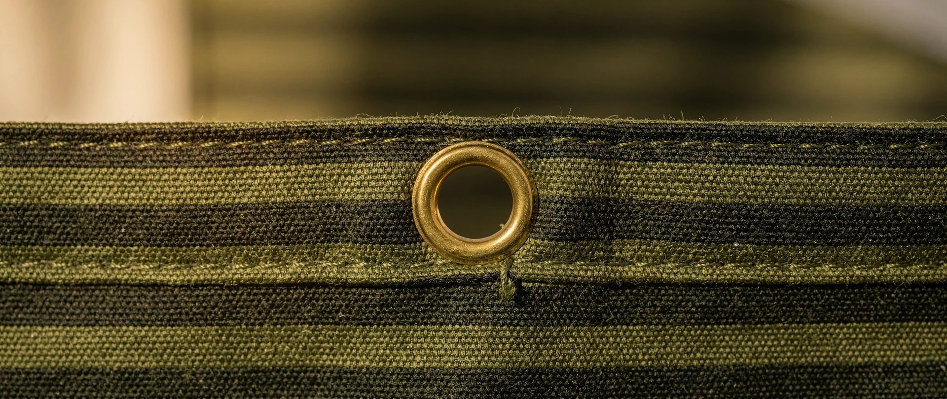 Olive striped outdoor canvas with a brass grommet set into the hem.
