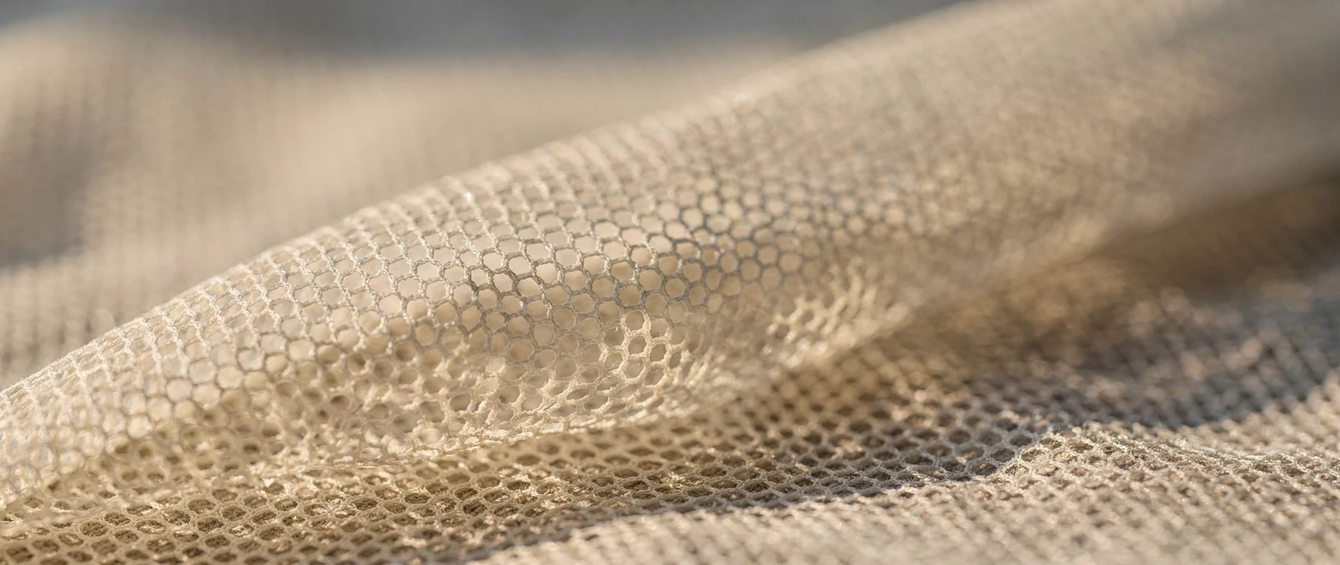 Fine ivory mesh with small hexagonal openings, draped in soft folds.