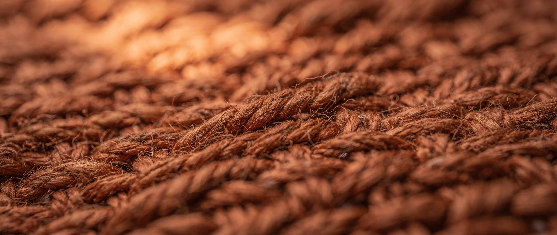 Thick twisted yarns in an earthy terracotta weave, shown in extreme close-up.