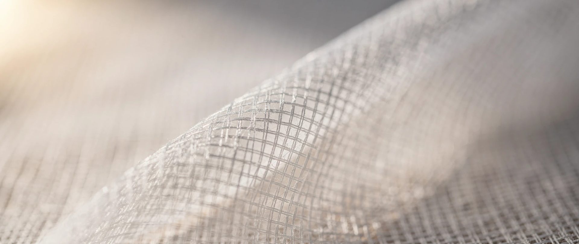 Voilage blanc très léger dont le tissage ajouré laisse voir chaque fil, avec un pli.